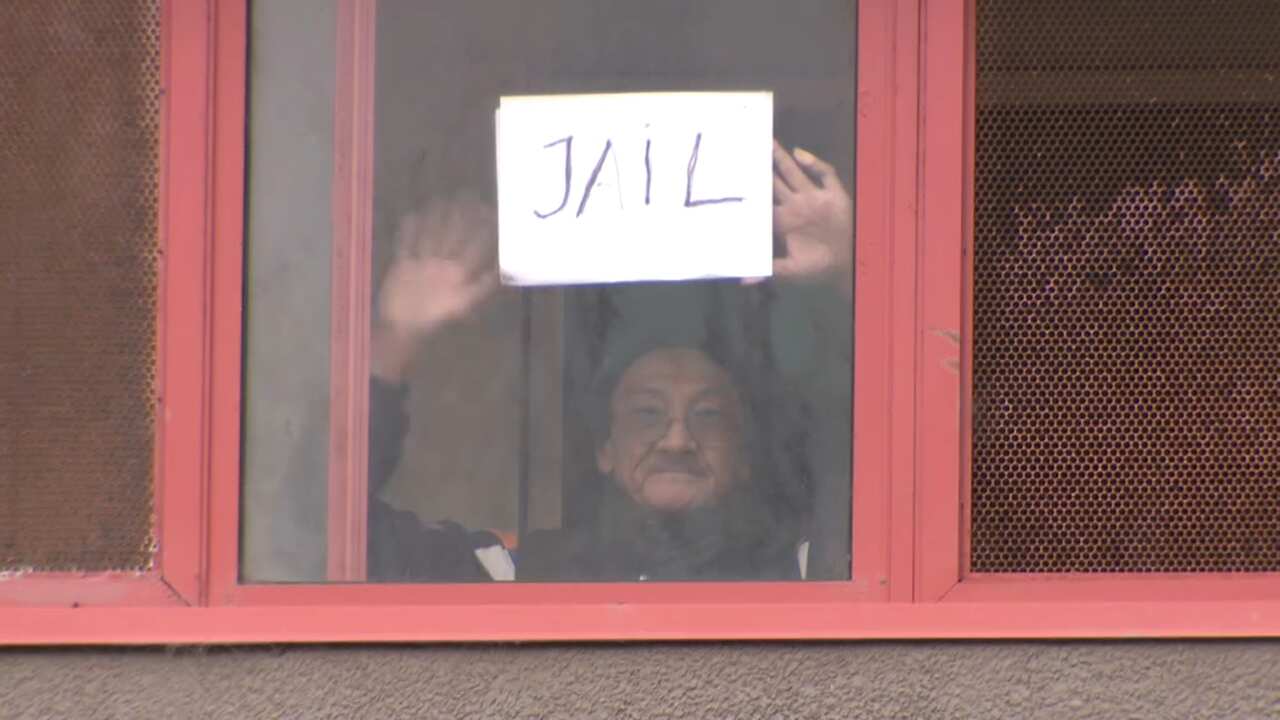 A resident of one of the towers holds a sign with the word 'jail' on it.