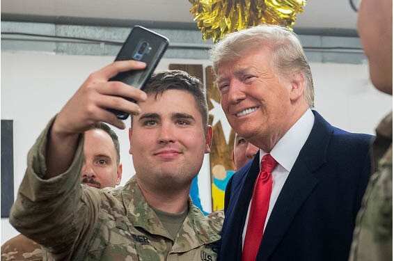 US President Donald Trump takes a photo as he greets members of the US military.