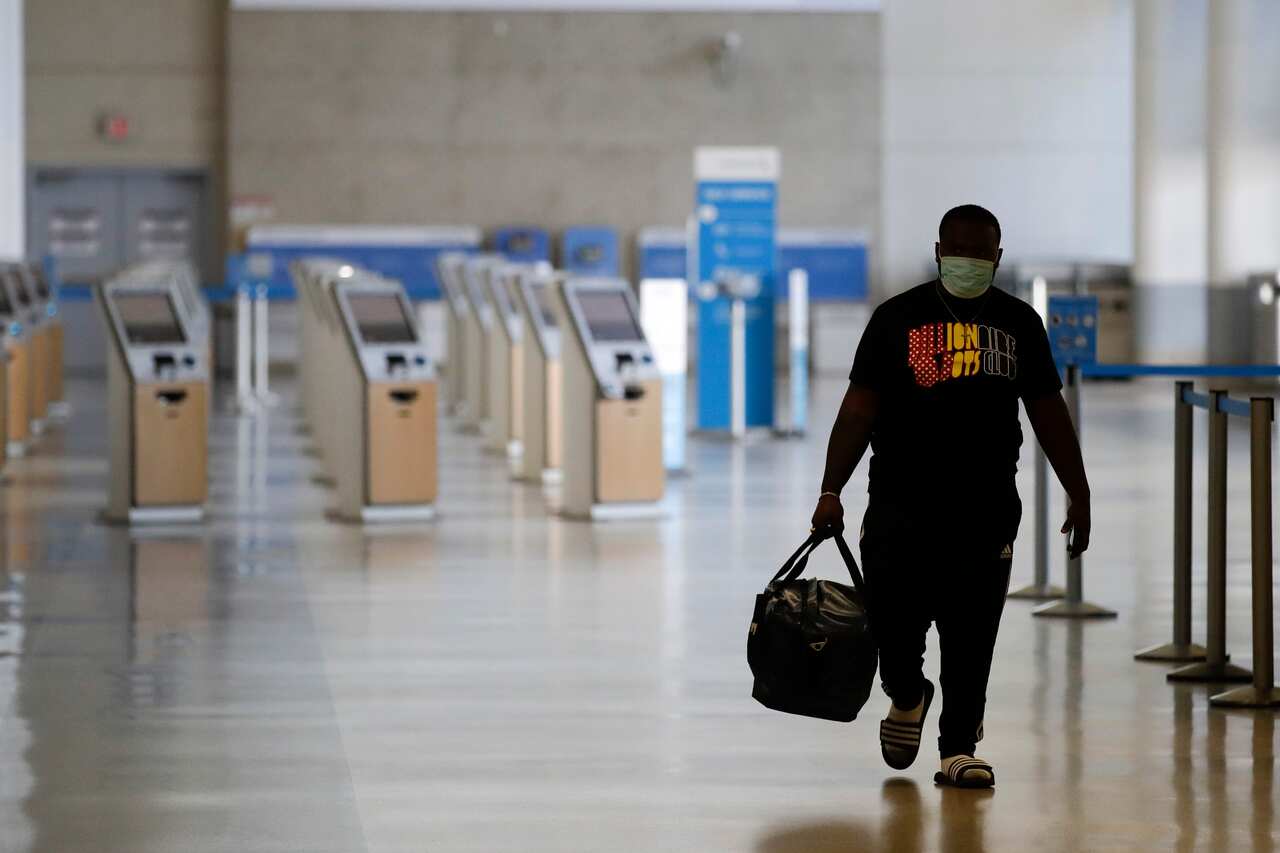 A traveler walks in a mostly empty American Airlines terminal at the Los Angeles International Airport in May, 2020.