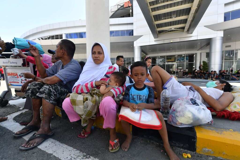 Earthquake-affected people wait for an evacuation flight by the Indonesian military at the airport in Palu, Indonesia's Central Sulawesi on September 30, 2018, following the September 28 earthquake and tsunami.