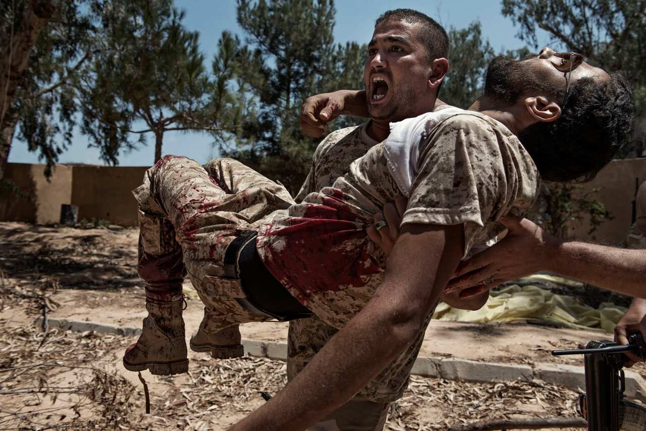 "We Are Not Taking Any Prisoners" shows a fighter of the Libyan forces carrying a comrade who was seriously injured seconds before by an ISIS booby trap.
