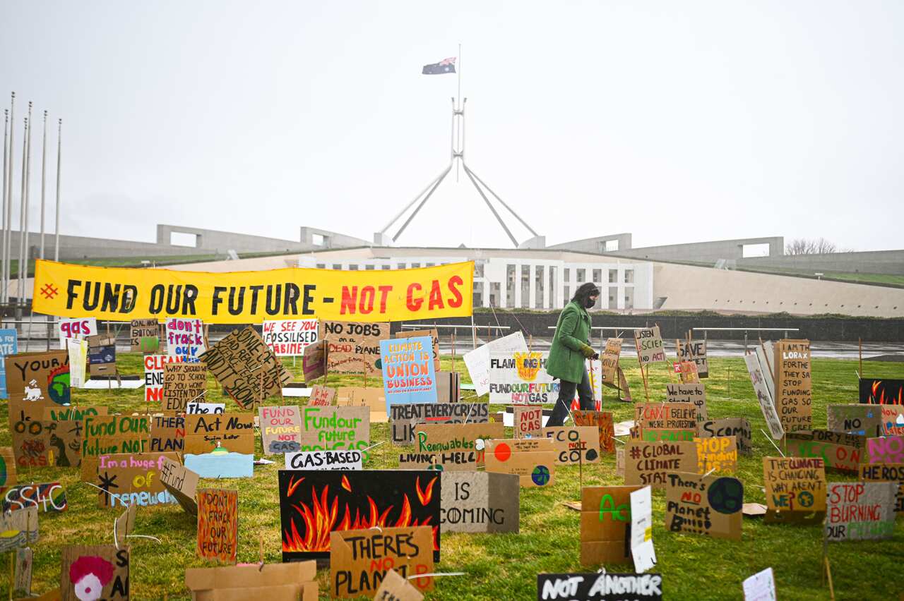 A school student walks amongst signs during a student climate protest outside Parliament House in Canberra, Friday, September 25, 2020. (AAP Image/Lukas Coch) NO ARCHIVING