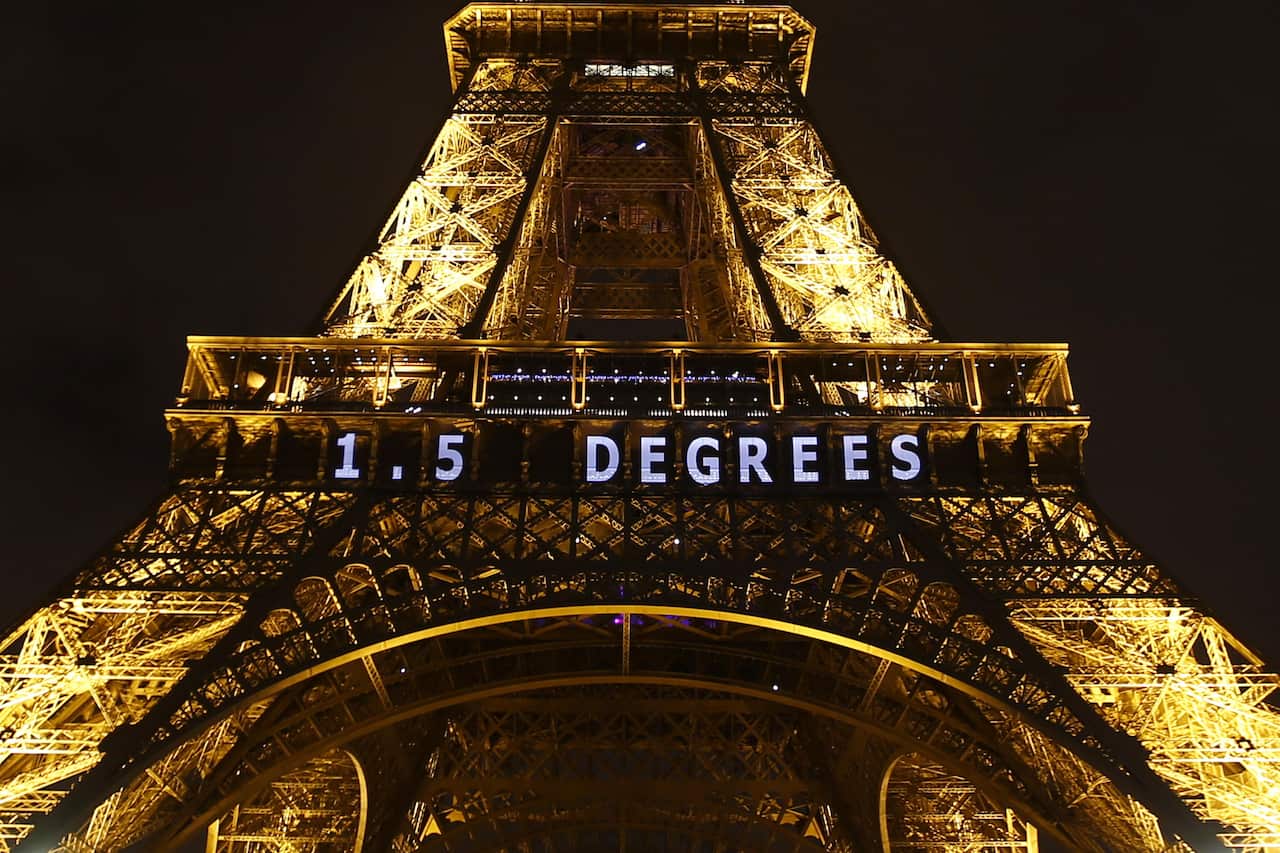 The slogan "1.5 DEGREES" is projected on the Eiffel Tower as part of the Climate Change Conference in Paris