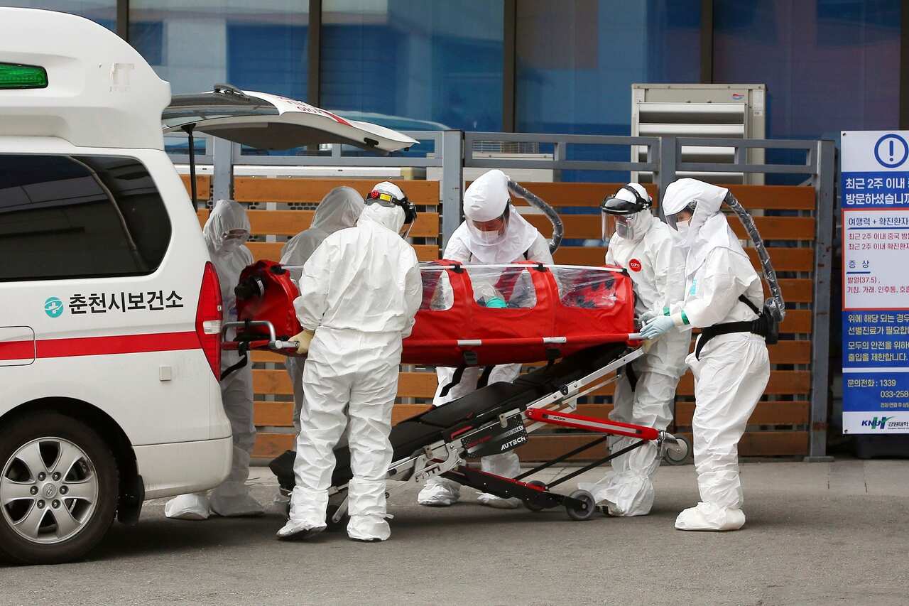 Medical workers wearing protective gears carry a patient infected with a new coronavirus to the hospital in Chuncheon, South Korea.