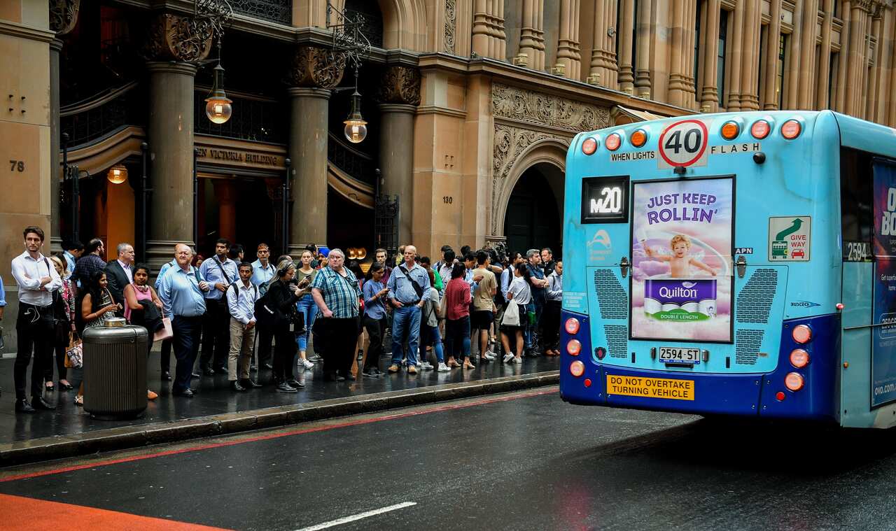 Commuters stand in a line as they wait for buses in Sydney's CBD.