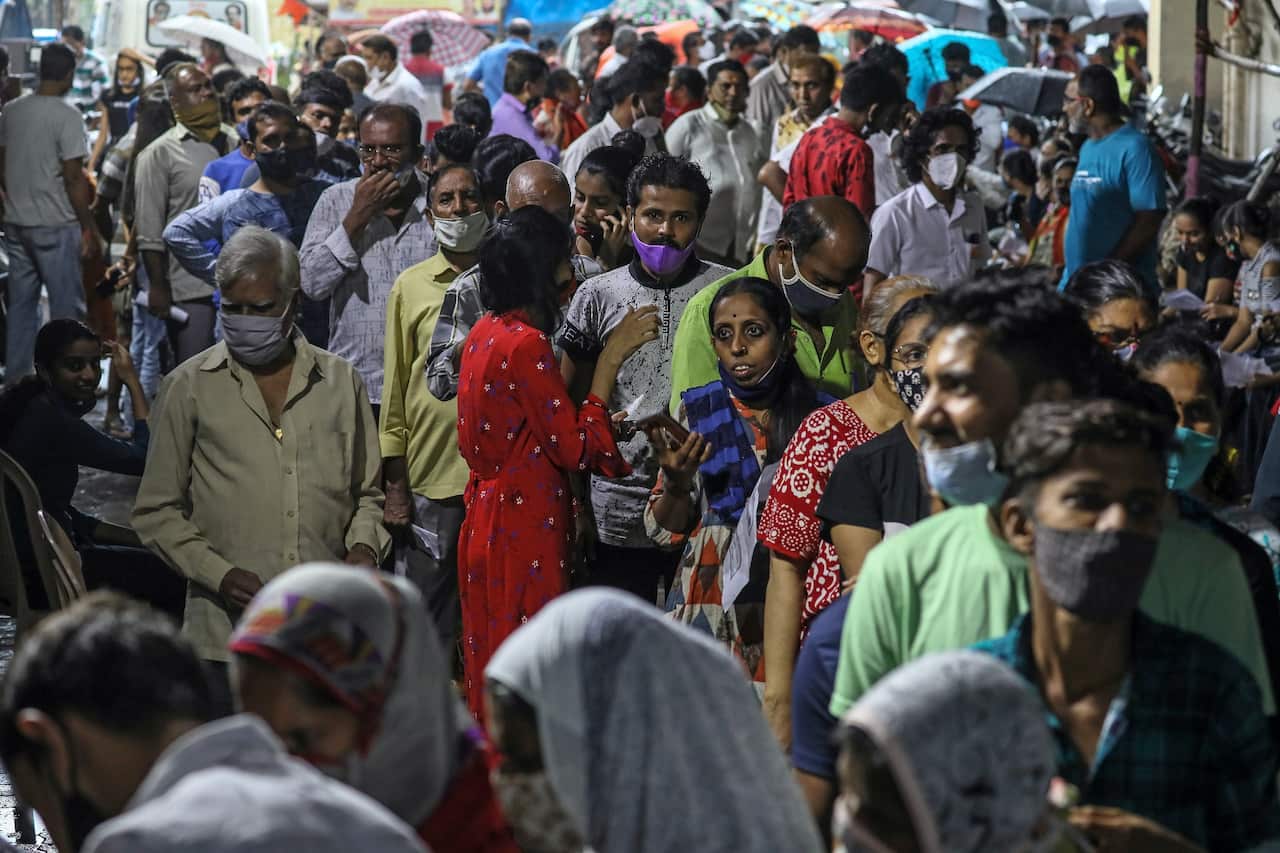 Indian people stand in a queue to receive a shot of the vaccine against COVID-19 during a mass vaccination drive in Mumbai.