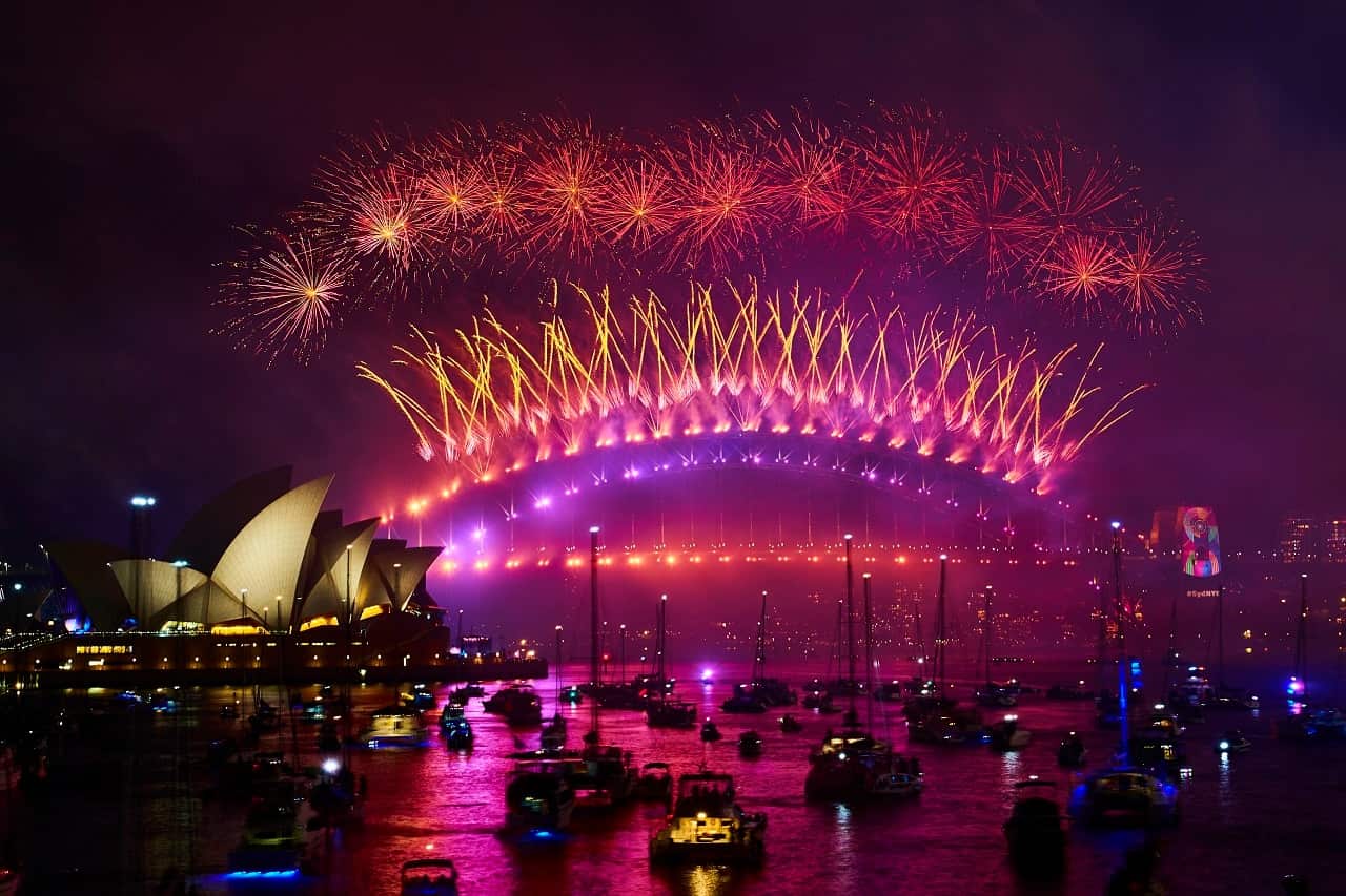Fireworks explode over the Sydney Harbour Bridge and the Sydney Opera House at midnight.