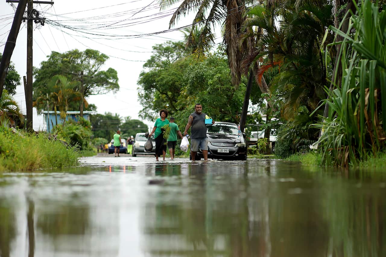 Residents wade through the flooded streets in Fiji's capital city of Suva on December 16, 2020, ahead of super Cyclone Yasa. 