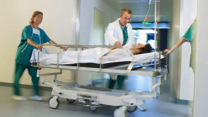 Doctors Moving Patient on gurney through hospital corridor