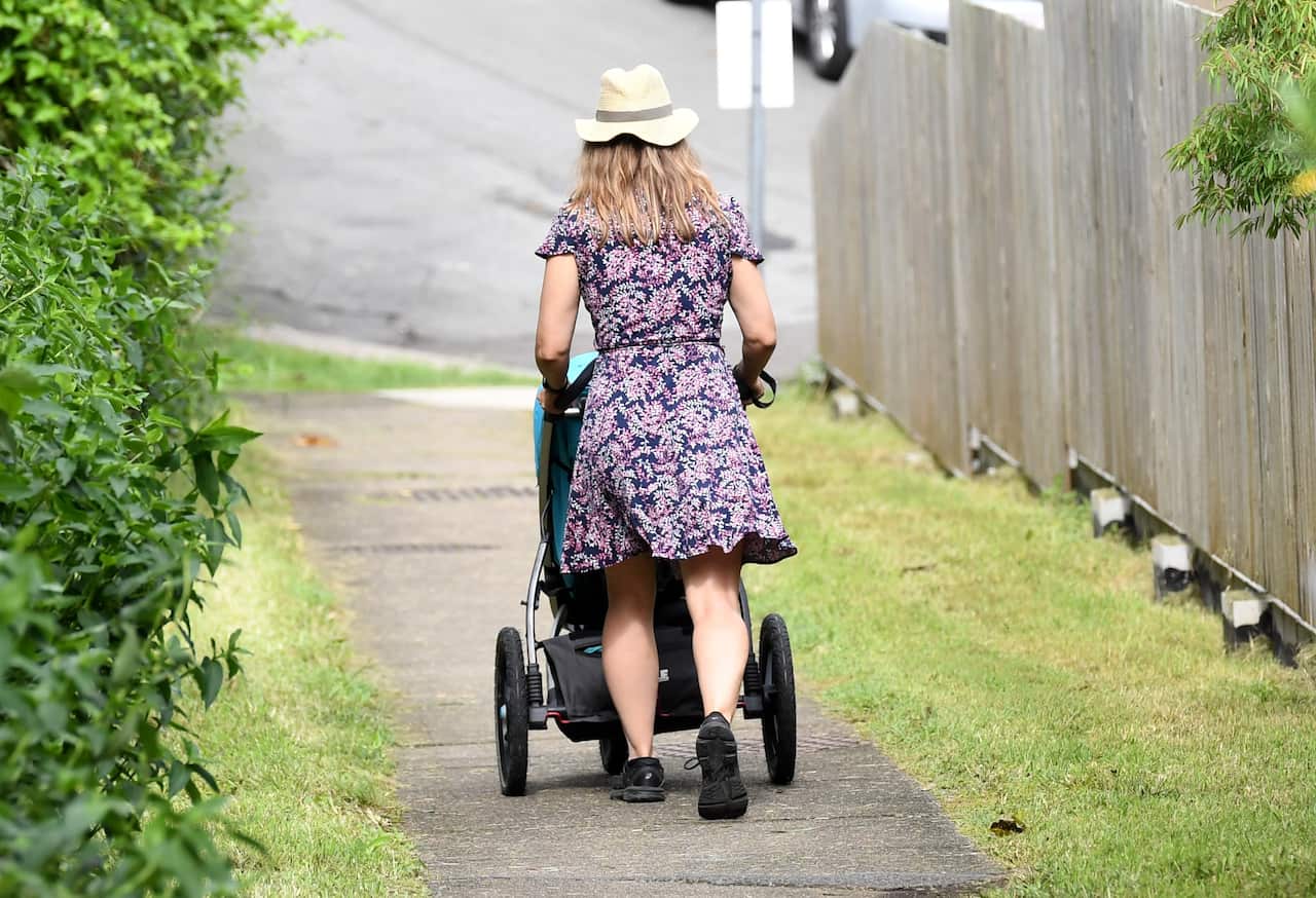 A mother pushes a stroller after picking up her child early from childcare in Brisbane.