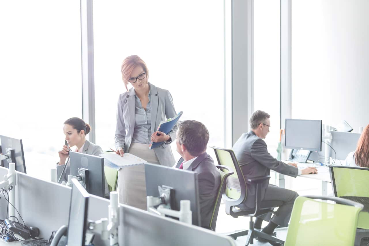 Business people working in open plan office with hot desks, but this close proximity will no longer take place between staff.