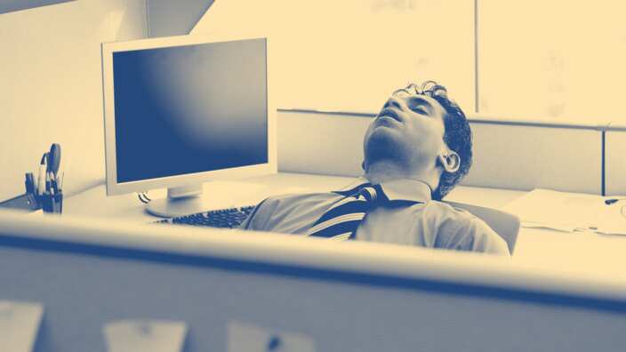 Businessman sleeping in cubicle