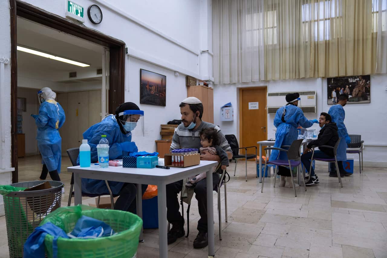 Israelis are tested for the coronavirus by healthcare workers at a COVID-19 testing center in Ramat Gan.