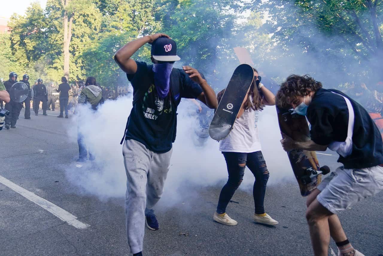 Demonstrators  run from tear gas used by police to clear the street near the White House in Washington, Monday, 1 June, 2020.