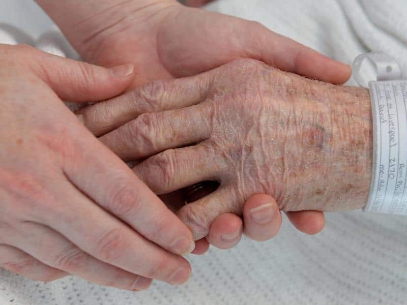 A nurse holds the hand of an elderly patient.