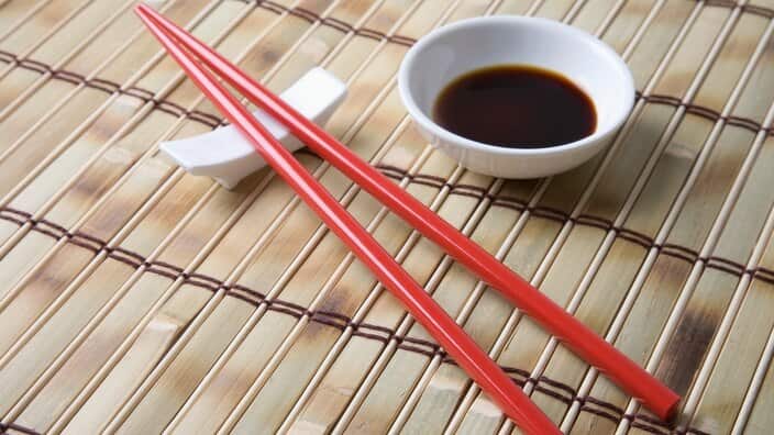 Red chopsticks and side bowl of soy sauce