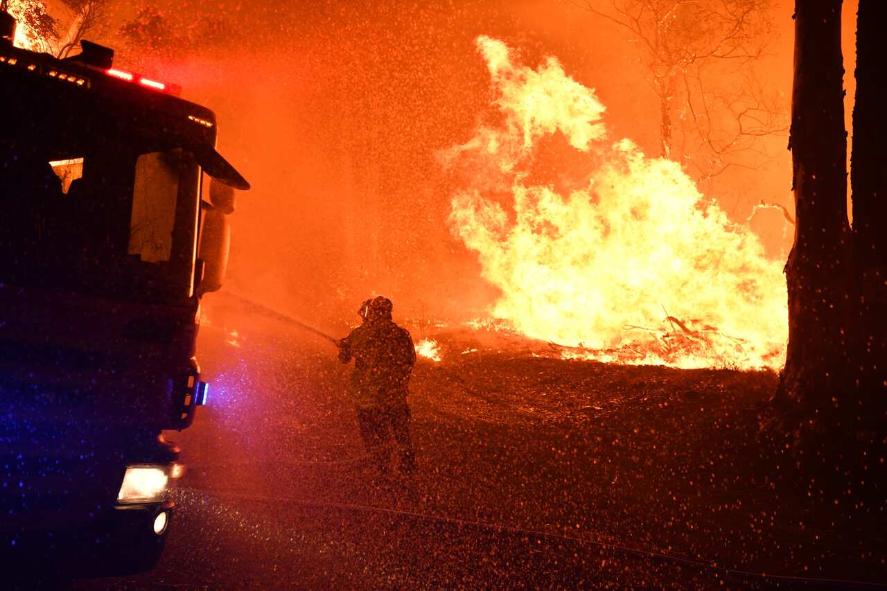 NSW Fire and Rescue officers battle a bushfire near Termeil on the Princes Highway between Batemans Bay and Ulladulla.