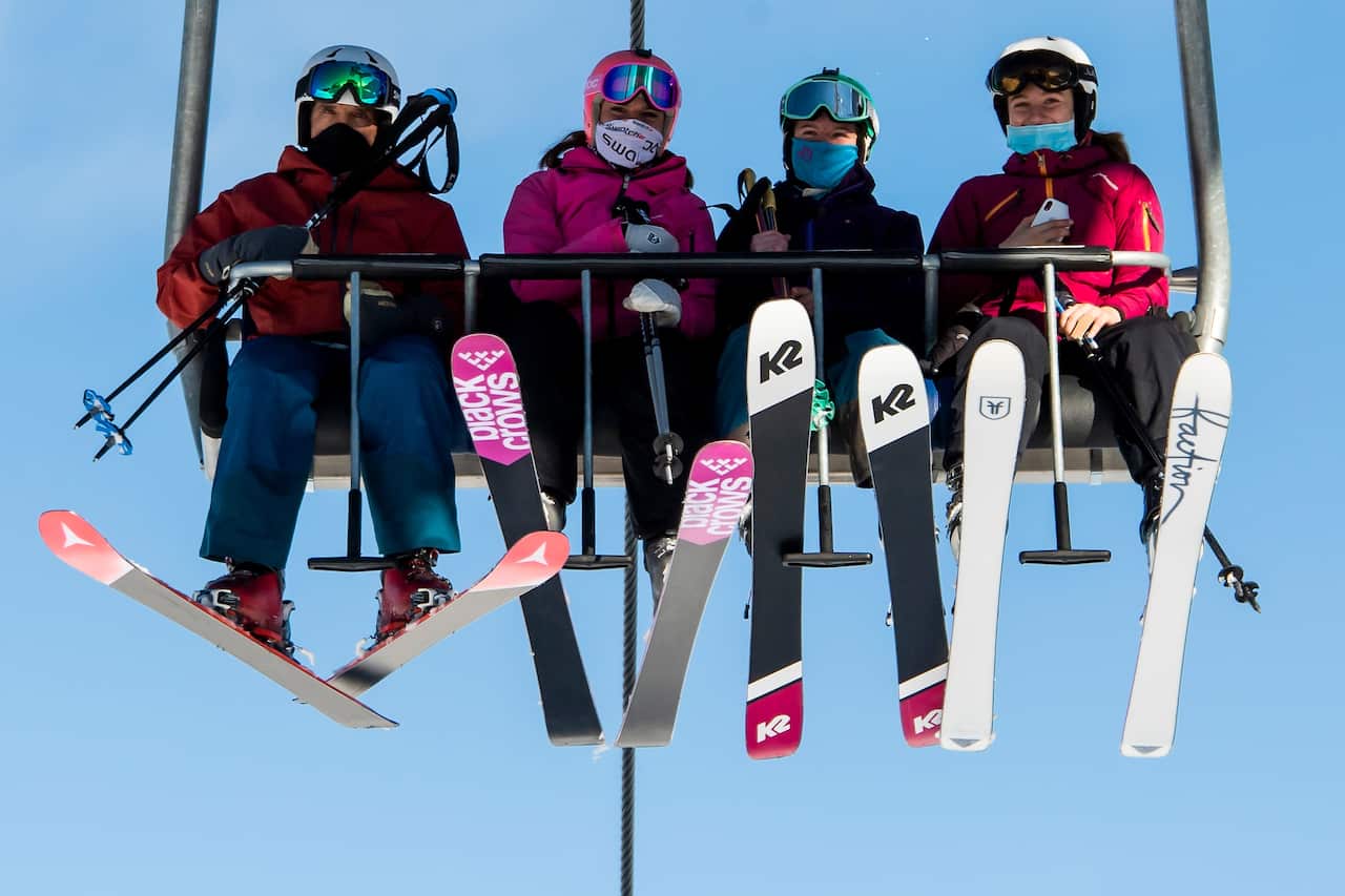 Skiers wearing face masks ride a chairlift on the opening day of the Verbier ski area in the Swiss Alps during the coronavirus pandemic.