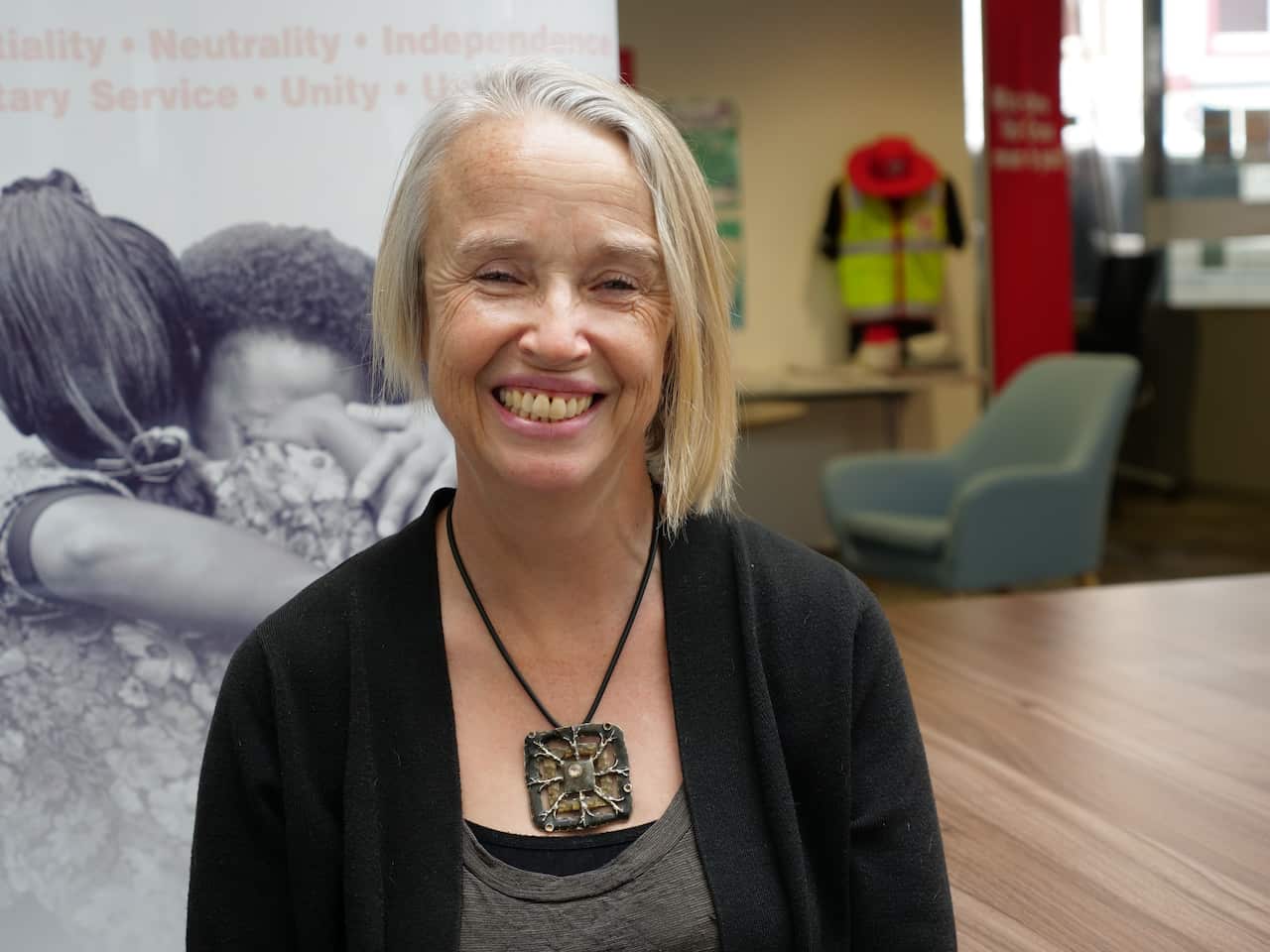 An older lady with short light hair and a big smile.