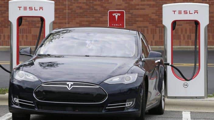 Tesla car recharges at a charging station