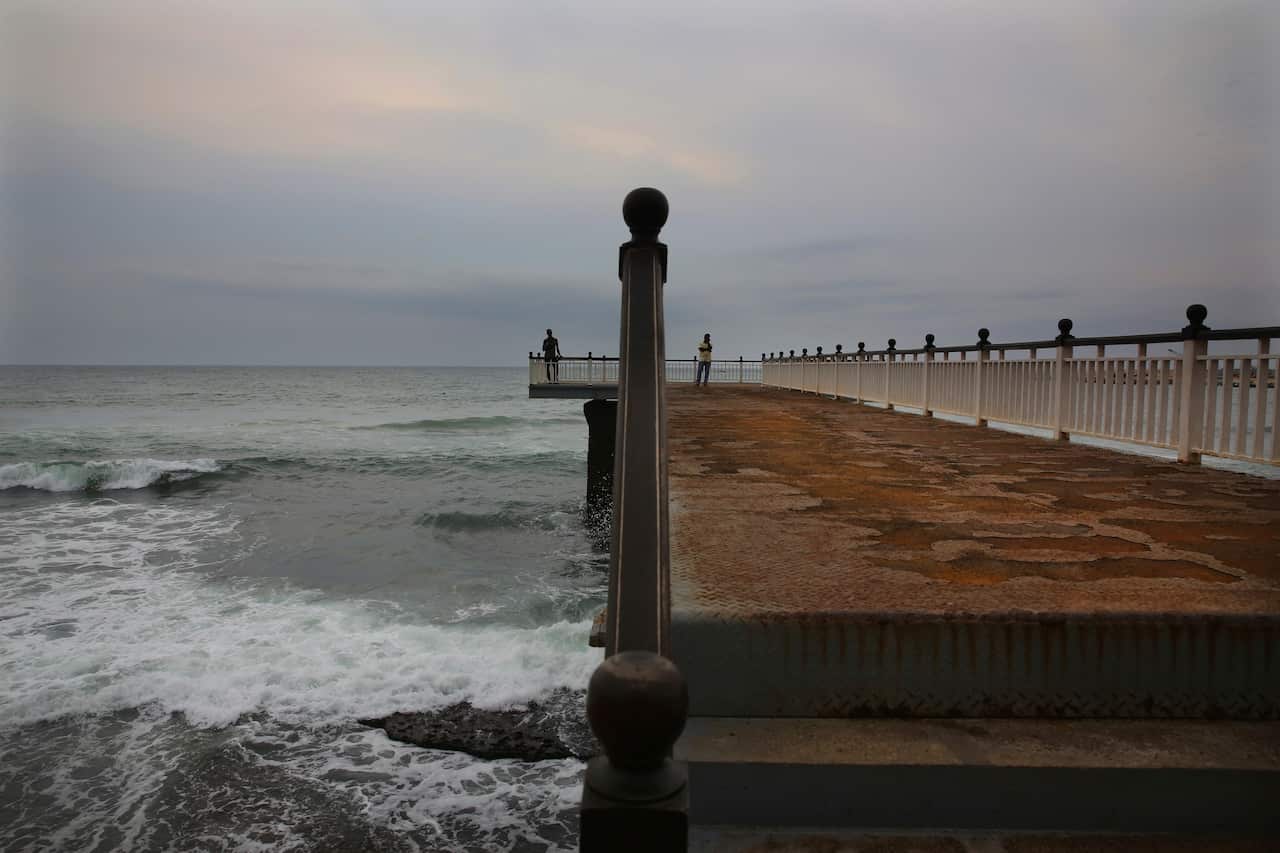 Sri Lankans stand at the deserted Galle face promenade jetty facing Indian ocean after the April blasts.