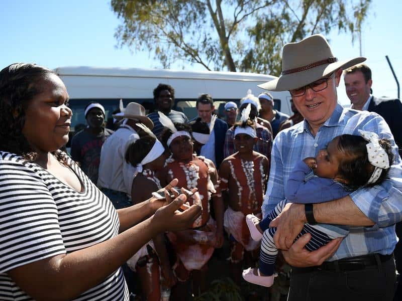 Malcolm Turnbull (R) holds a baby on arrival at Tennant Creek
