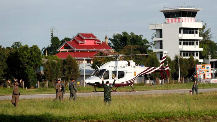 Thai soldiers and police officers secure the area as a helicopter lands to evacuate a boy that was trapped in a cave to a hospital.