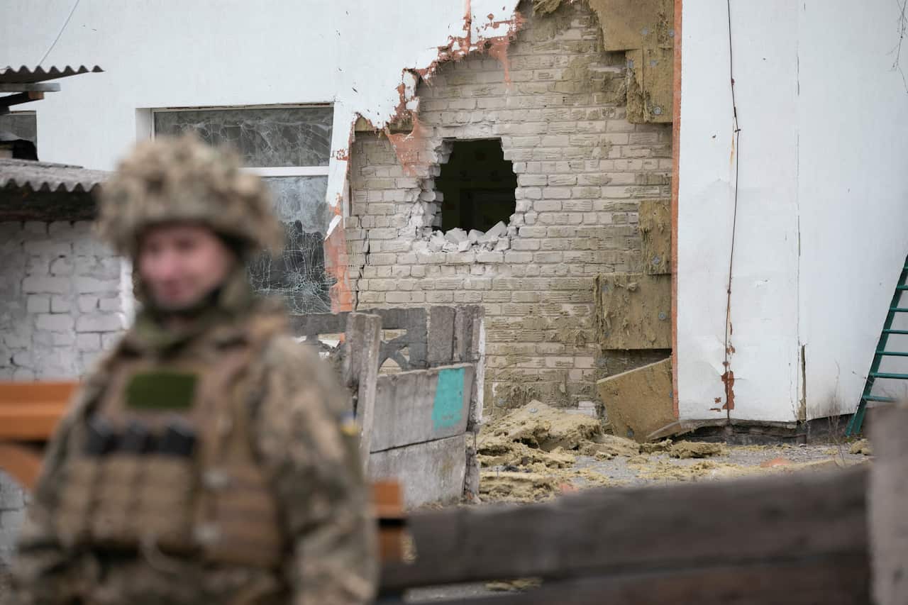 A Ukrainian soldier stands next to a damaged wall after the reported shelling of a kindergarten in the settlement of Stanytsia Luhanska, Ukraine, 