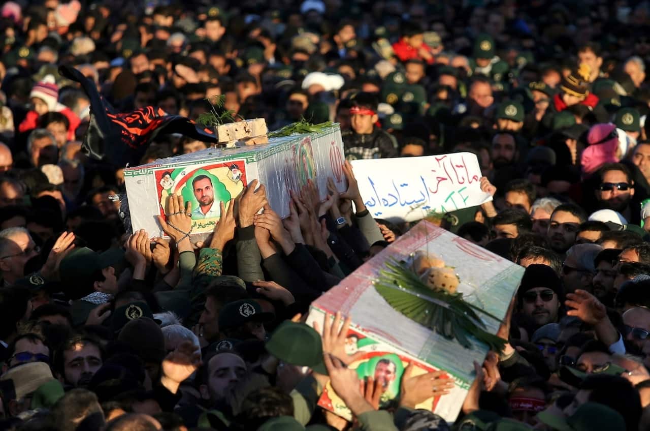 Mourners carry flag-draped caskets during a mass funeral for those killed in a suicide car bombing that targeted members of Iran's powerful Revolutionary Guard.