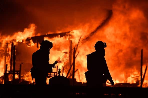 Firefighters douse flames as a home burns in the Napa wine region in California on October 9, 2017, as multiple wind-driven fires continue to whip through the region.