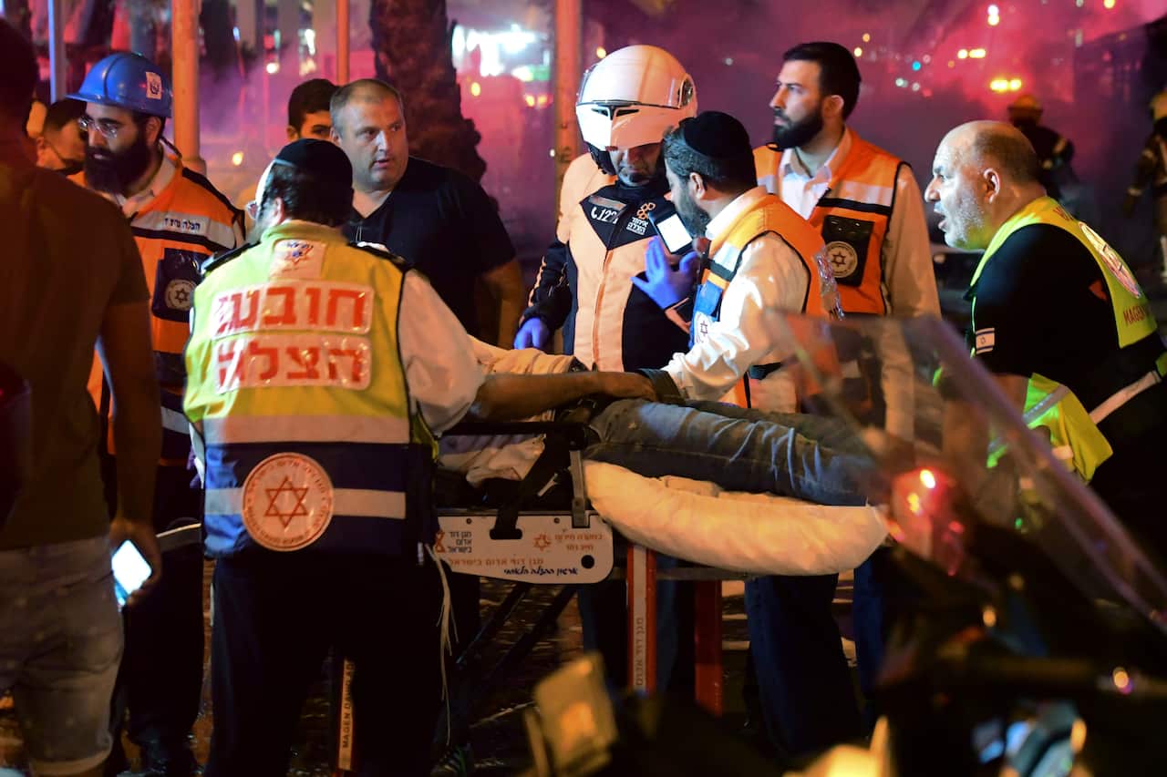 Israeli medics evacuate a wounded man after a rocket fired from the Gaza Strip hit the central Israeli town of Holon, near Tel Aviv, Tuesday, May 11, 2021.