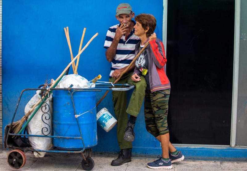 In this April 3, 2018 photo, street cleaners take a break as they work on the main boulevard in Holguin, Cuba.