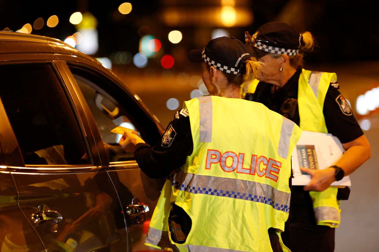 Police speak to a driver at a road block near the Queensland-NSW border.