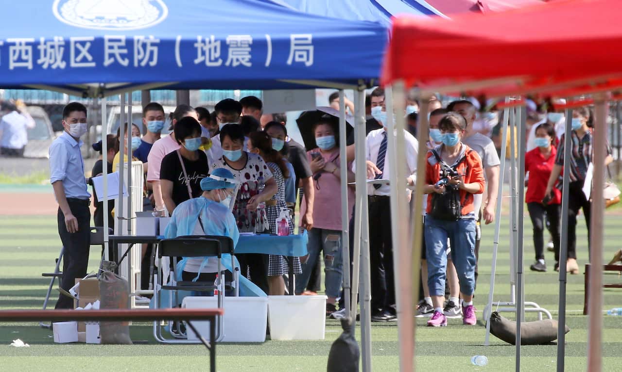 Beijing Health authorities conduct polymerase chain reaction (PCR) test for people and market workers to detect a coronavirus infection at a football stadium.