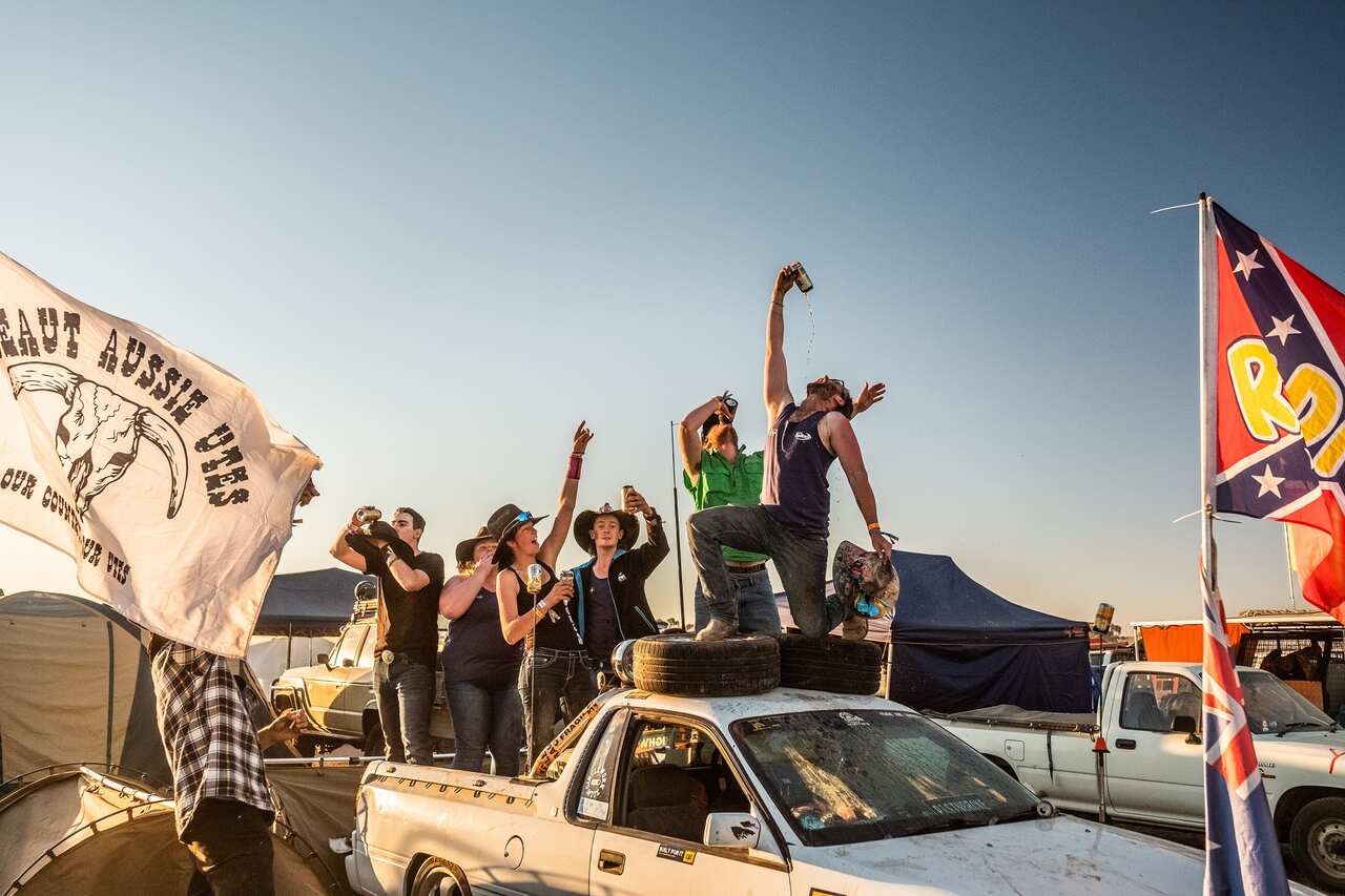 Rhys Martini pours a drink into his mouth as he stands atop a ute at the Deni Ute Muster.