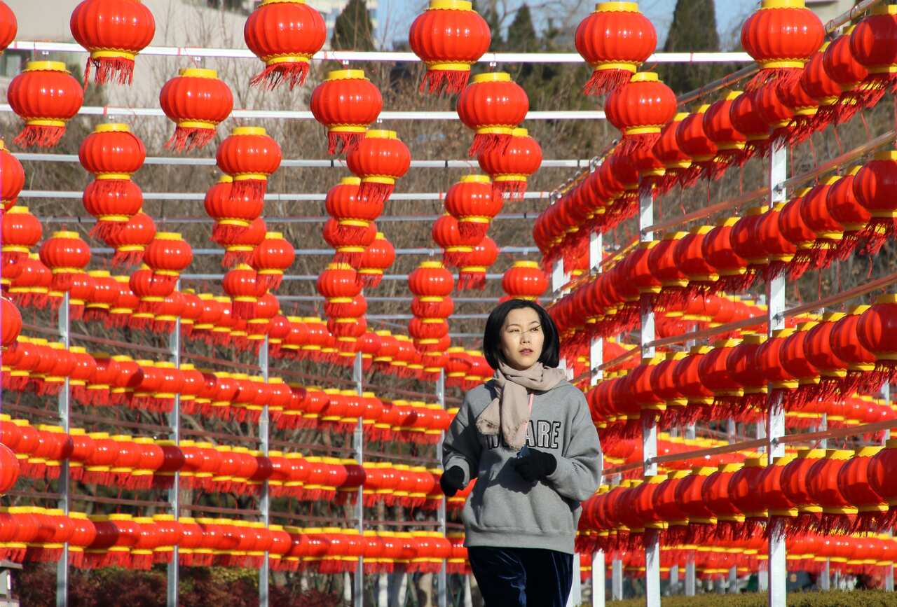 A woman runs under a sea of red lanterns.  