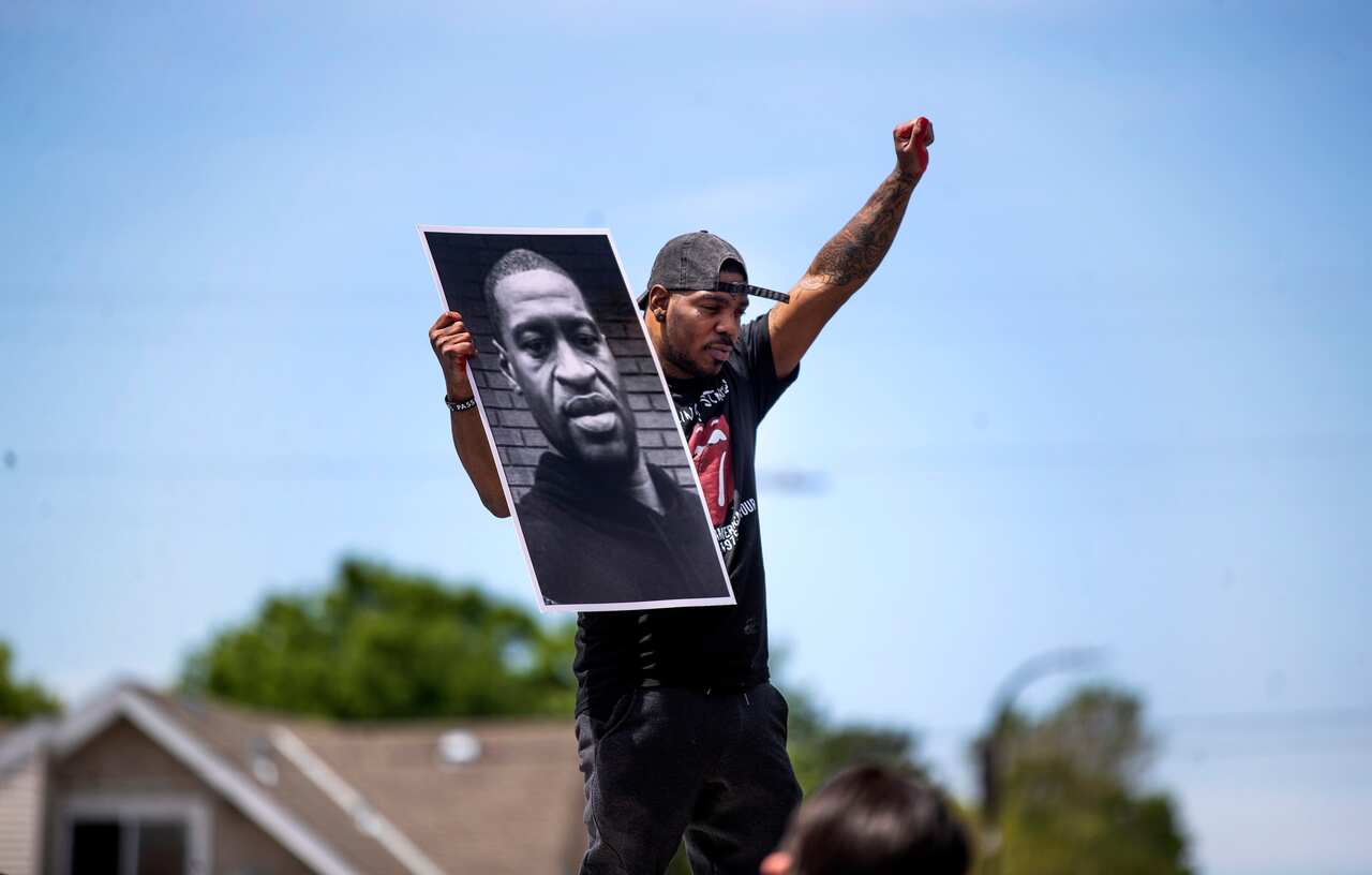 A supporter holds a photo of George Floyd on the site where the 46-year-old died in police custody. 