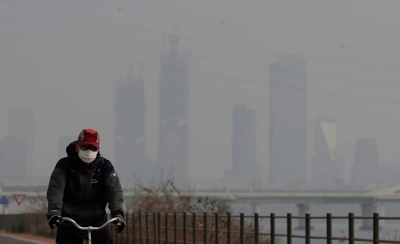 A man wearing a mask rides a bicycle along the Han river in Seoul, South Korea.