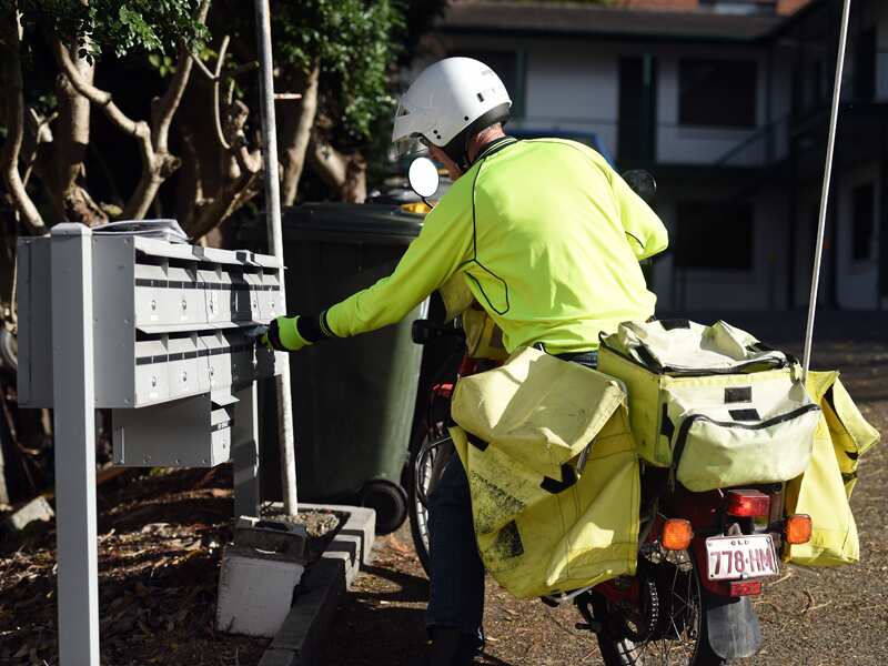 A postman on a motorbike delivers letters