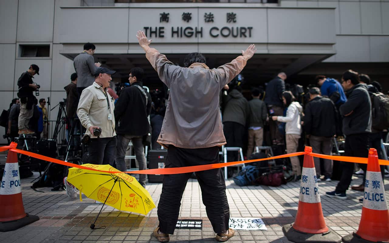 A pro-democracy supporter with a yellow umbrella shouts slogans outside the High Court in Hong Kong, China, 17 January 2018.