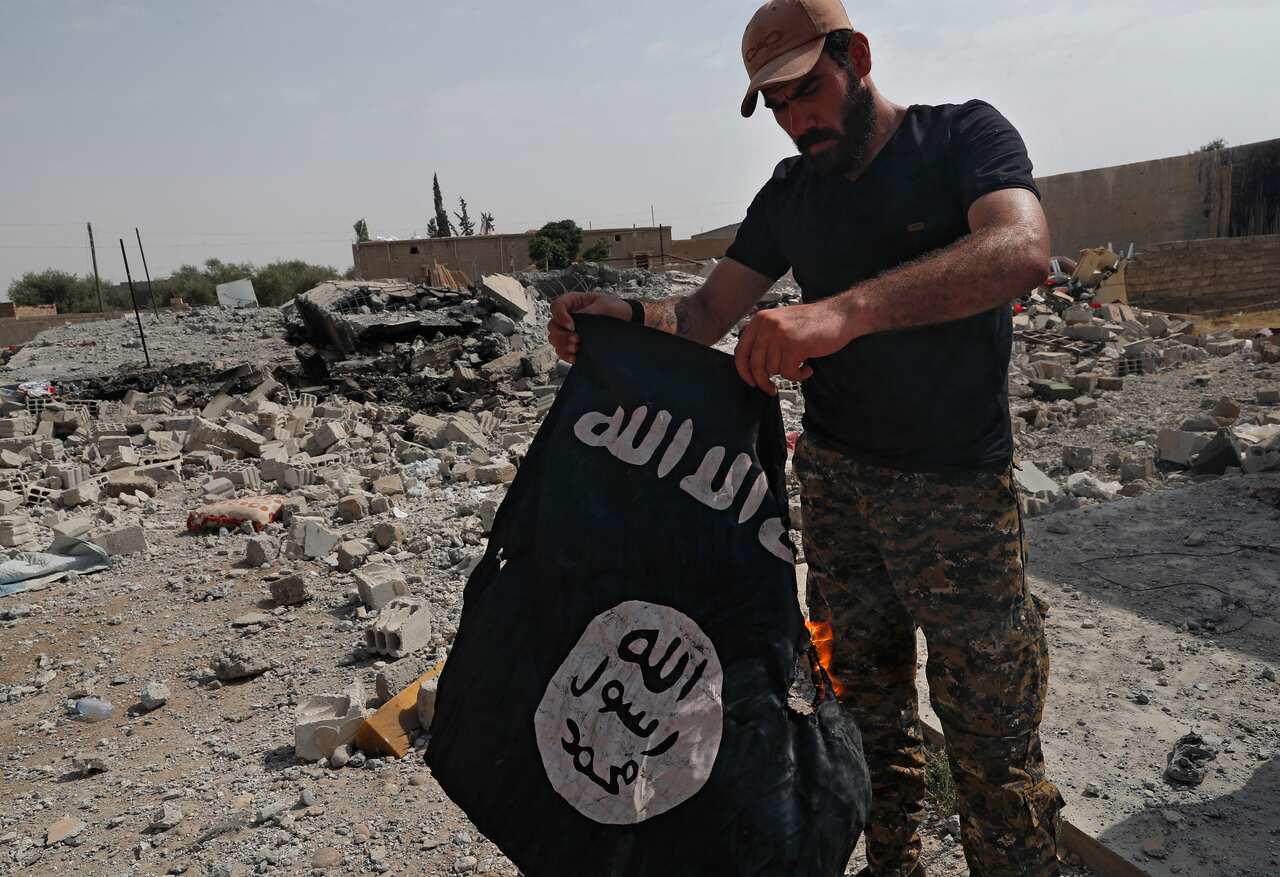 A Syrian militiaman holds up a captured banner of the so-called Islamic State after the militants were pushed out of Raqqa, northeast Syria.