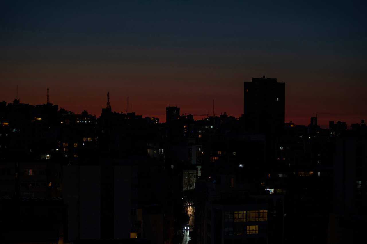 sun sets on city skyline and the buildings have no power