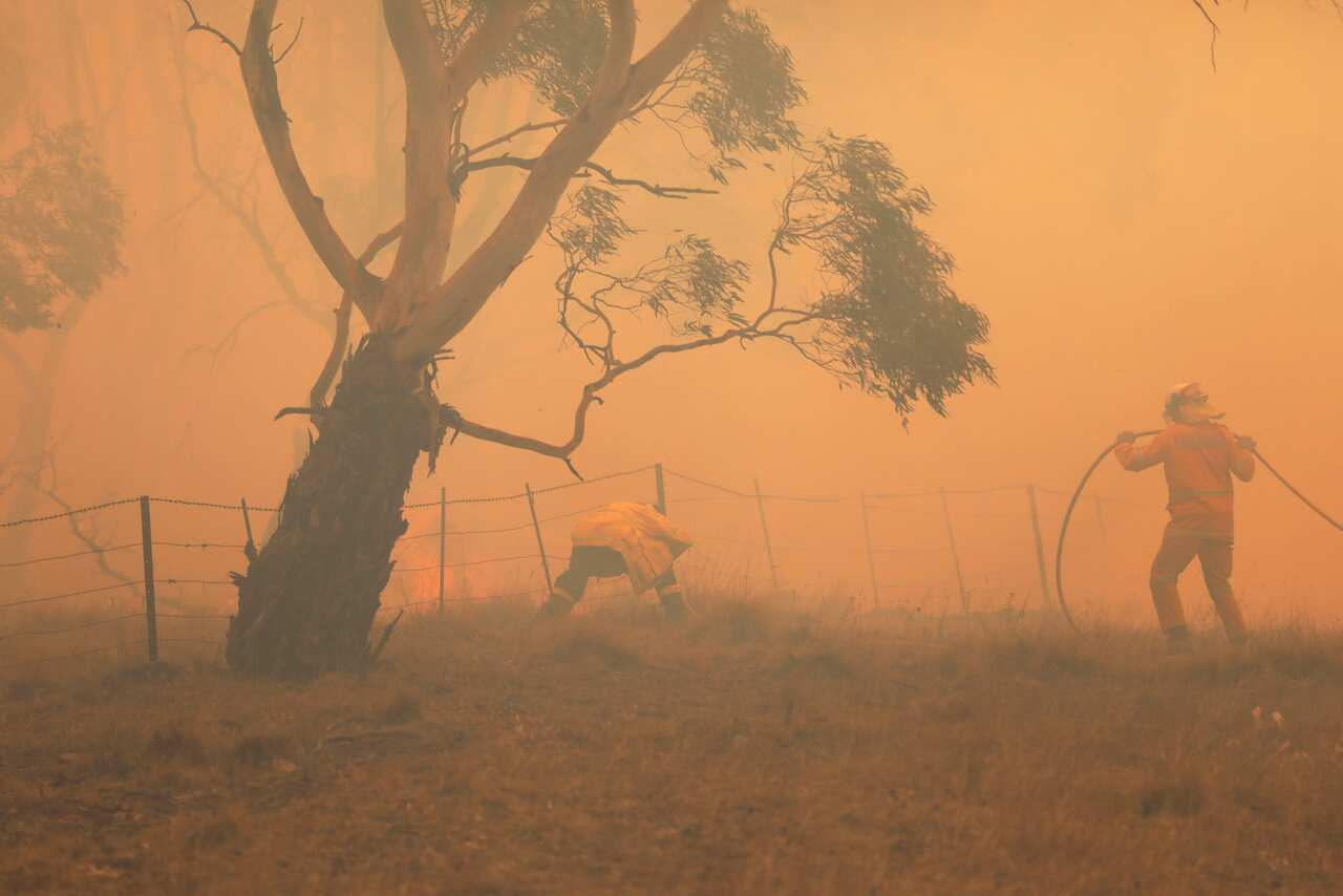 NSW RFS crews extinguish a fire that crossed the Monaro Highway, four kilometres north of Bredbo, Sunday, February 2, 2020.