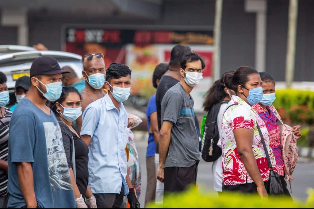 Residents wearing face masks waiting to cross the main road in the Fijian capital Suva.
