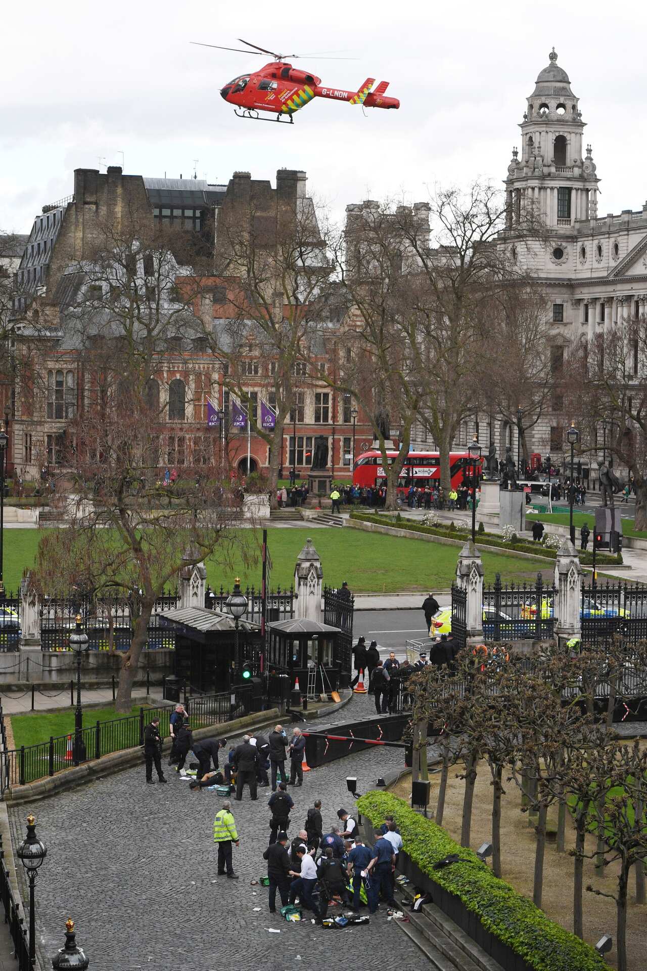 An Air Ambulance lands as emergency services attend a man (top) and a police officer (bottom) outside the Palace of Westminster.