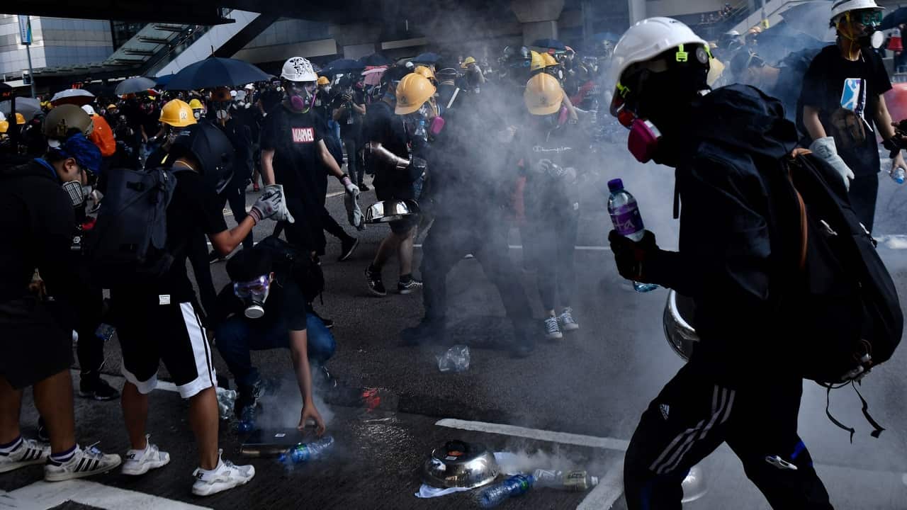 Protesters attempt to contain tear gas fired by the police in the Admiralty area during a general strike in Hong Kong.