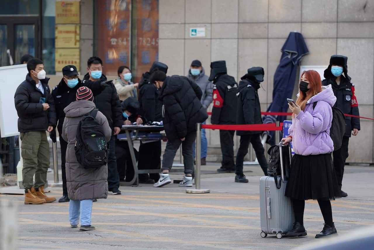 A woman pushes her luggage past a health check point in Beijing.