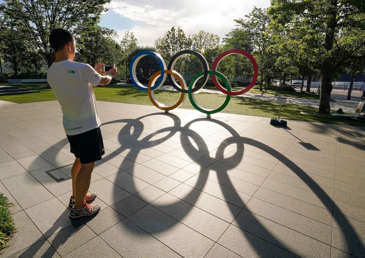 A visitor takes a photo of the Olympic Rings monument near the New National Stadium in Tokyo, Japan.