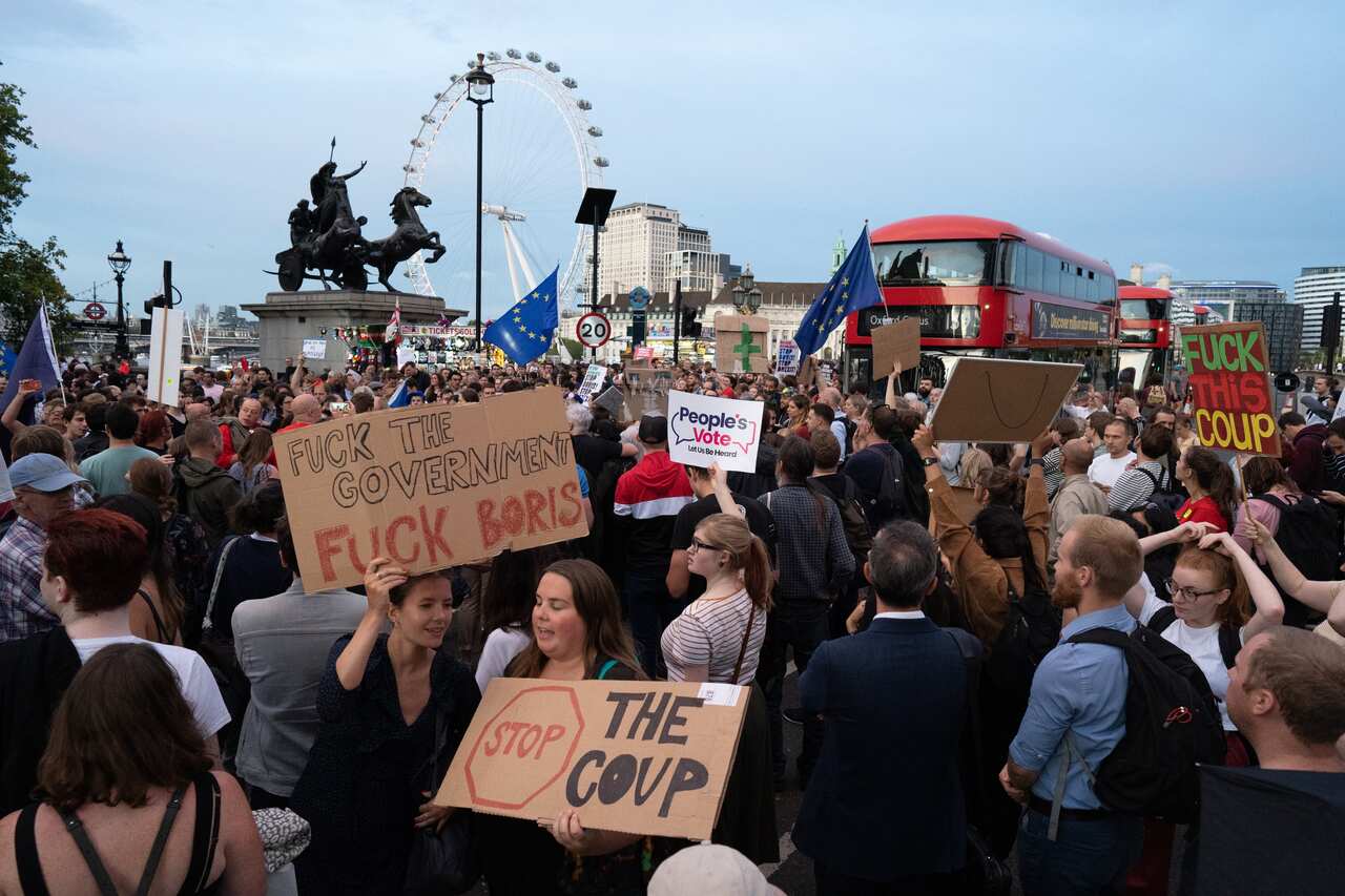 Hundreds of people are seen protesting against Boris Johnson outside the houses of parliament on Westminster bridge.