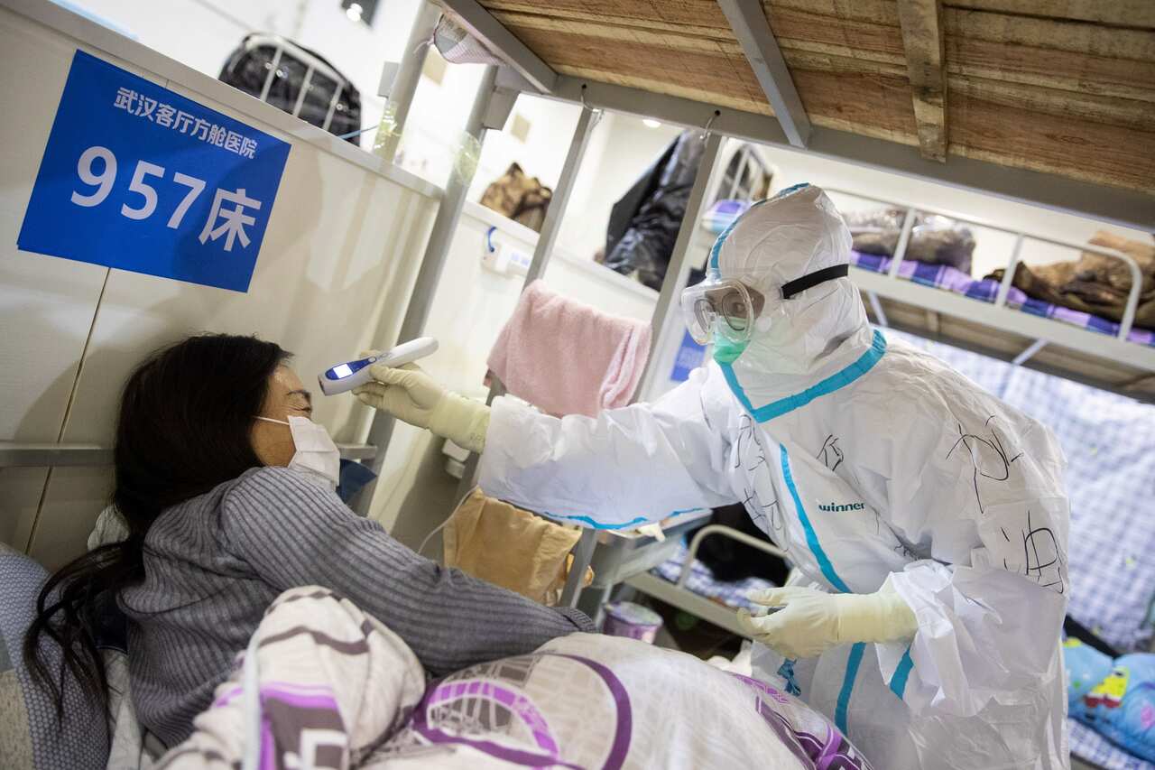 A medic working inside a makeshift hospital in Wuhan, China, checks the temperature of a patient in April, 2020.